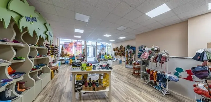 Blick in den Laden: Regal mit Palmenkronen voller Kinderschuhe, Mützenständer und die Schaufensterfront