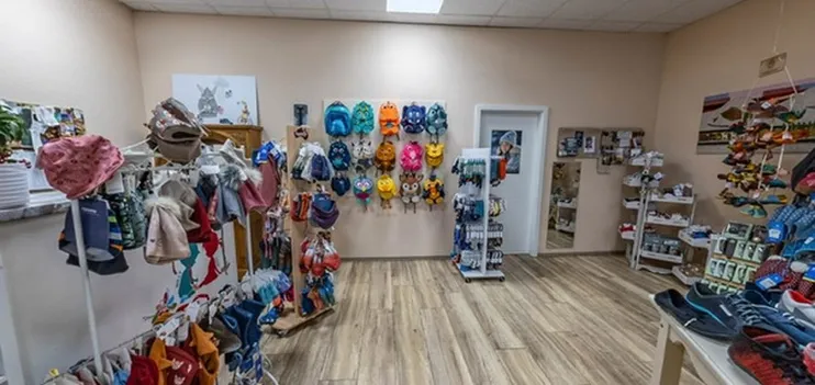 Ecke im Laden mit Kinderrucksäcken an der Wand, Mützen, Socken und Sandalen